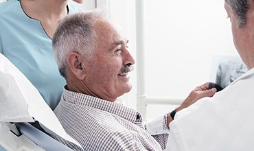 Older male patient smiling at dentist