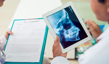Dentists look at patient chart and x-rays on tablet