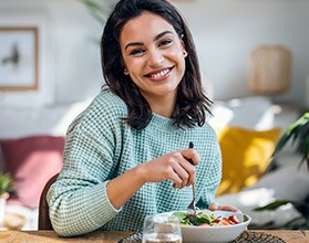a smiling woman eating a salad