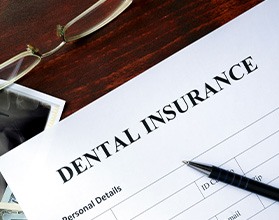 A dental insurance form and dental X-rays set on a wooden table