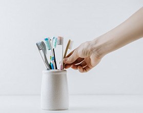 Hand reaches for toothbrush