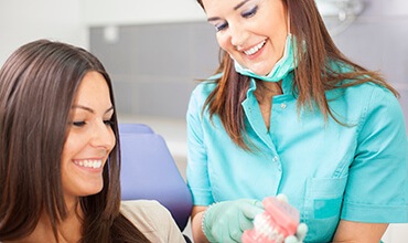 Female patient and dentist looking at mouth model