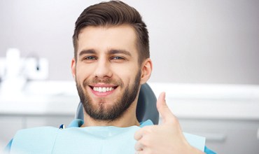 Man giving thumbs up in dental chair