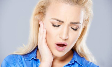 Woman with dental emergency holding jaw in pain