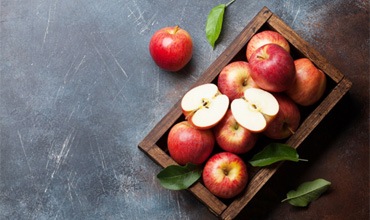 Several apples and leaves in a wooden box