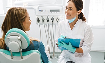 Smiling dentist taking notes on clipboard