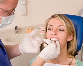 A dentist in Chevy Chase fitting a female patient with an Invisalign aligner