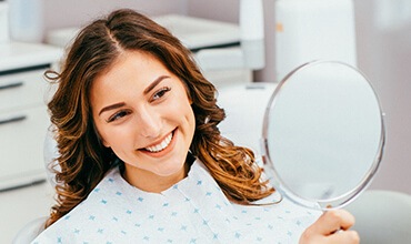 Woman examines smile in mirror