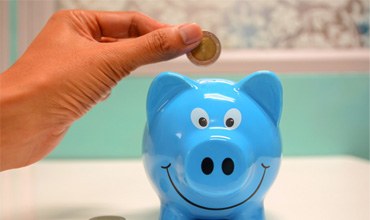 Hand putting a coin in piggy bank