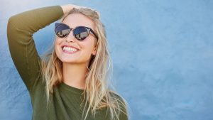 woman in sunglasses smiling with veneers in Chevy Chase