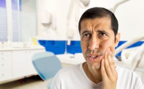 Man holding his cheek in pain before seeing an emergency dentist in Chevy Chase