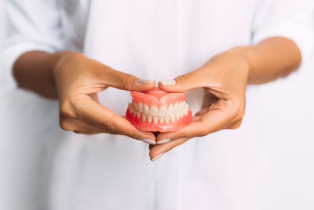 A dentist’s hands holding a pair of dentures.