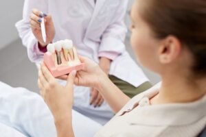 Dentist showing patient a dental implant model.
