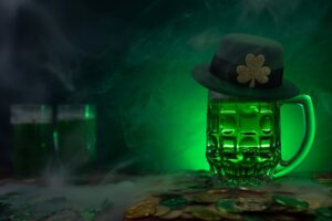Green beer topped with green derby hat with glowing green background. 